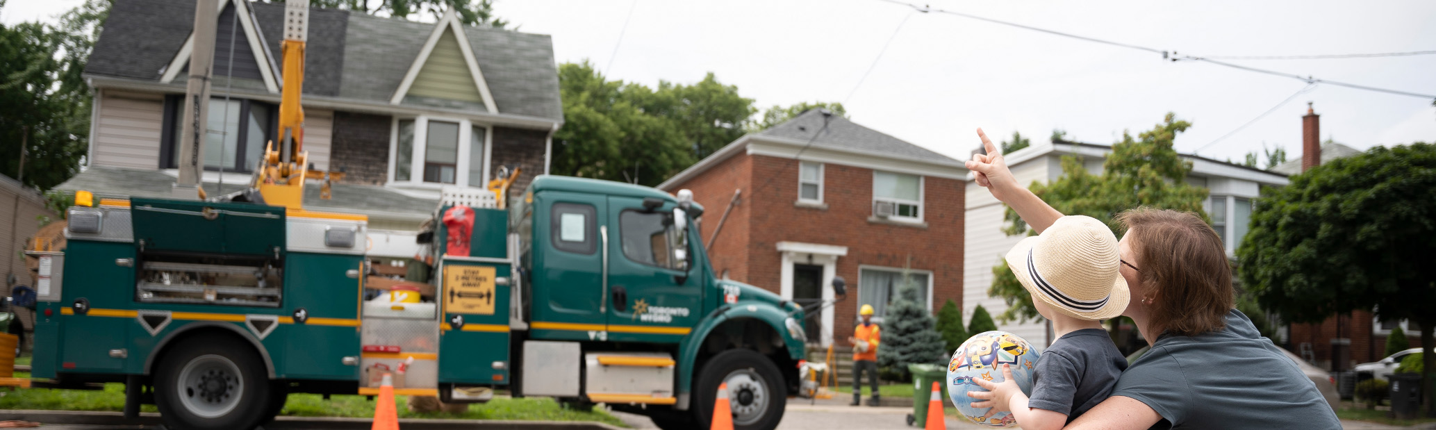 Mom and child looking at Toronto Hydro bucket truck.'