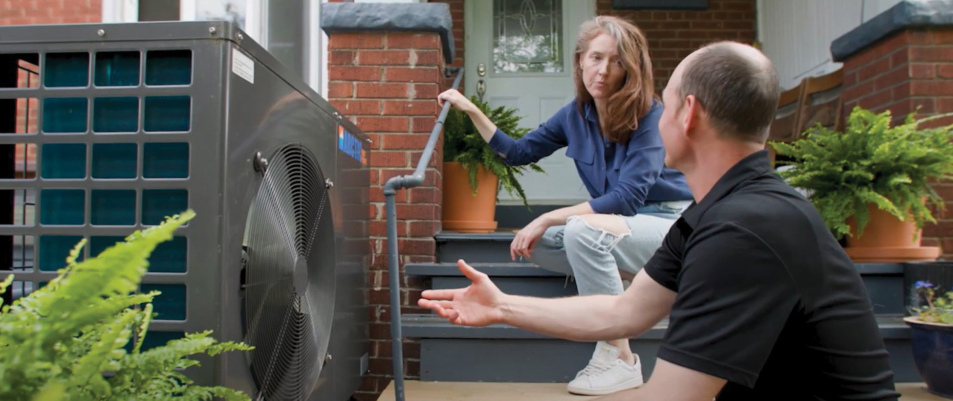 Toronto Hydro energy coach and Toronto homeowner taking a look at the homeowner's electric heat pump.